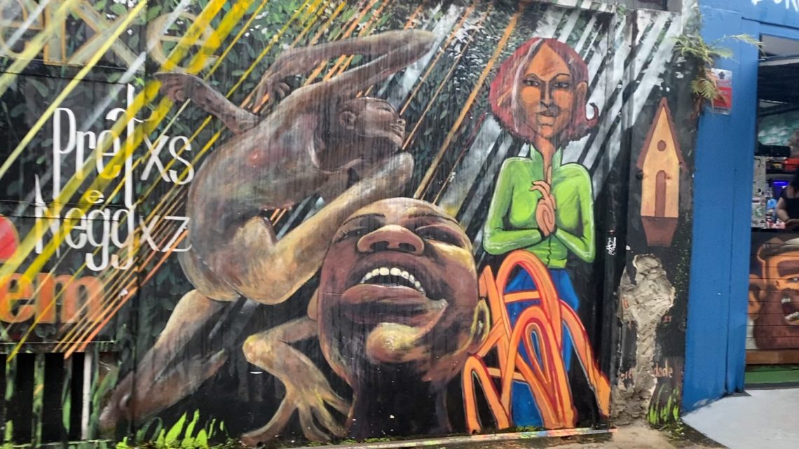 Mural urbano en São Paulo con rostros expresivos y figuras en colores vivos