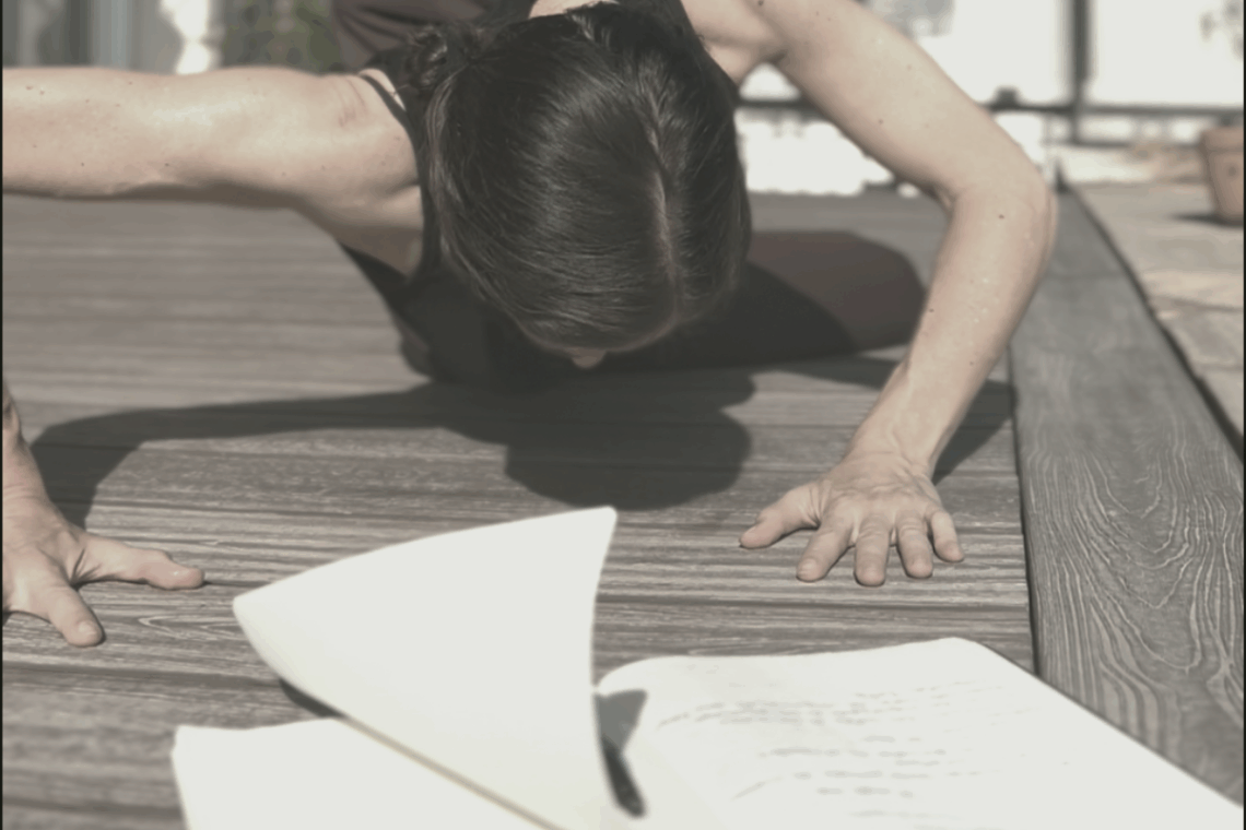 Mujer en movimiento, con el cuerpo inclinado y los brazos junto a un cuaderno que deja volar una página al viento