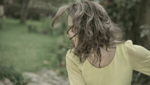 Claudia Mendizábal en gesto de movimiento al aire libre, con blusa amarilla